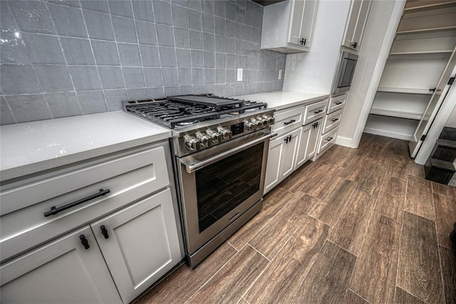 kitchen featuring white cabinets, decorative backsplash, and stainless steel stove