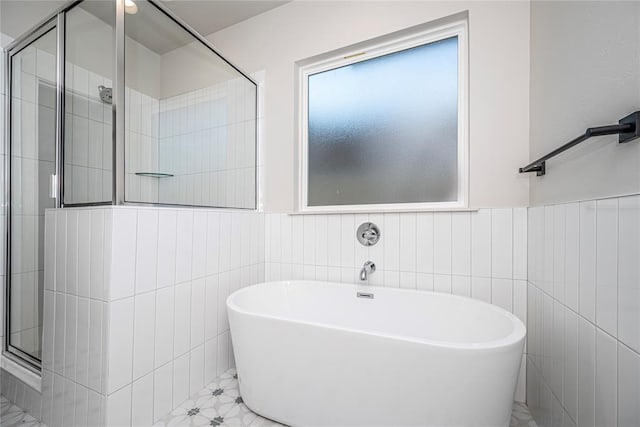 bathroom with tile walls and independent shower and bath