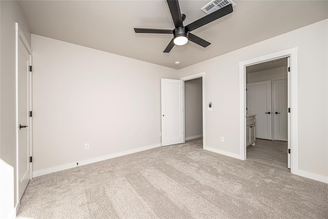 unfurnished bedroom with ceiling fan, ensuite bath, and light carpet