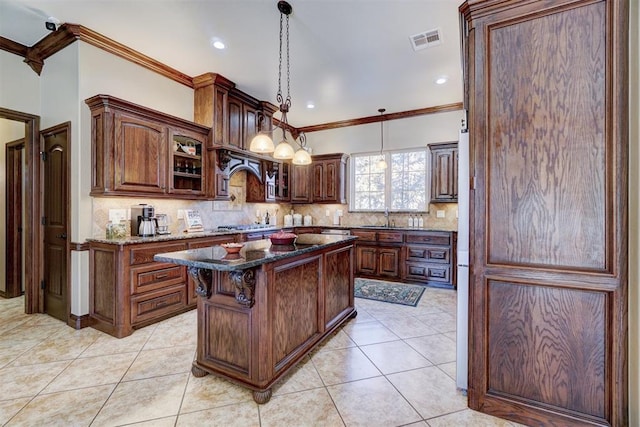 kitchen with dark stone counters, hanging light fixtures, a kitchen island, and light tile patterned floors