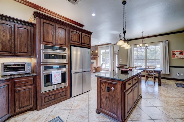 kitchen featuring a kitchen island, appliances with stainless steel finishes, pendant lighting, dark stone counters, and ornamental molding