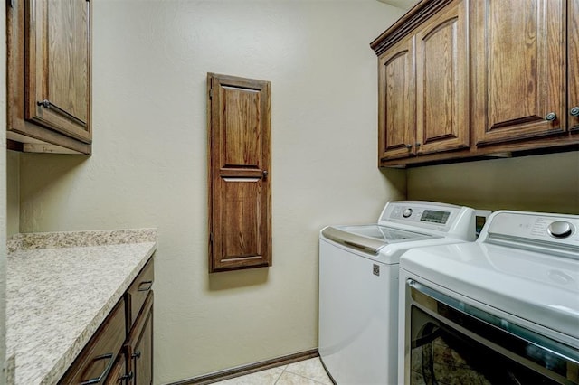 laundry room with cabinets, washing machine and dryer, and light tile patterned floors