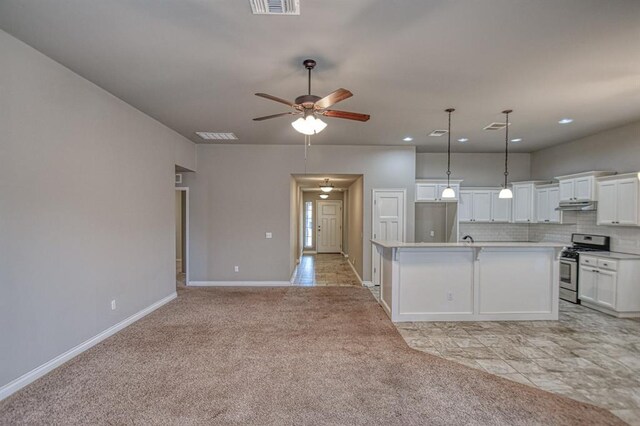 kitchen with appliances with stainless steel finishes, white cabinetry, light carpet, an island with sink, and decorative backsplash