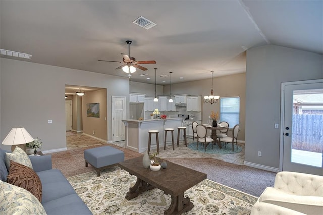 carpeted living room with ceiling fan with notable chandelier and lofted ceiling