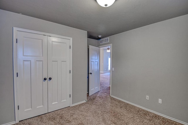 unfurnished bedroom featuring light colored carpet and a closet