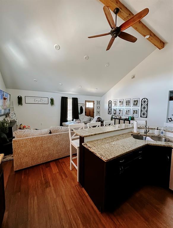 kitchen featuring ceiling fan, a center island with sink, vaulted ceiling with beams, sink, and dark hardwood / wood-style flooring