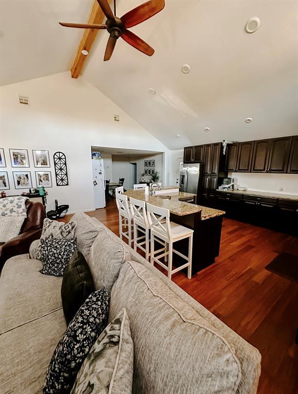 living room featuring ceiling fan, vaulted ceiling with beams, dark hardwood / wood-style floors, and sink