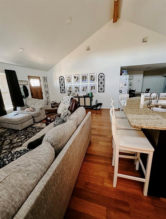 living room with high vaulted ceiling, sink, dark hardwood / wood-style floors, and beamed ceiling