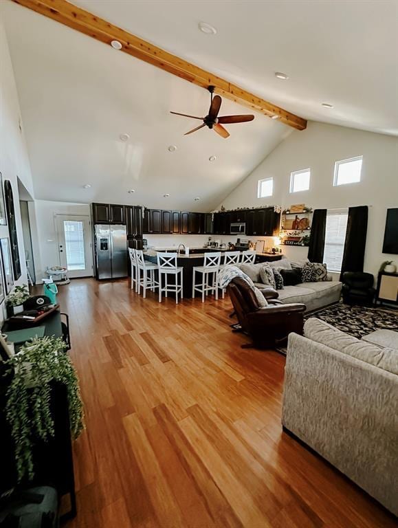 living room with high vaulted ceiling, hardwood / wood-style floors, beam ceiling, and ceiling fan