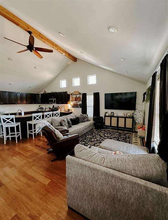 living room featuring wood-type flooring, beamed ceiling, sink, high vaulted ceiling, and ceiling fan