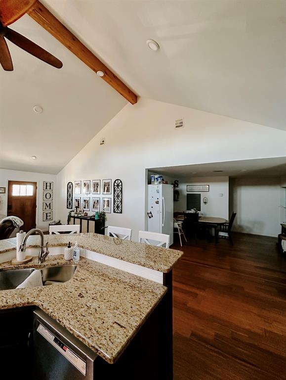 kitchen featuring a center island with sink, black dishwasher, dark hardwood / wood-style floors, sink, and lofted ceiling with beams