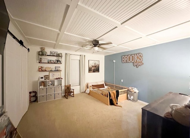 bedroom with ceiling fan, a barn door, and carpet floors