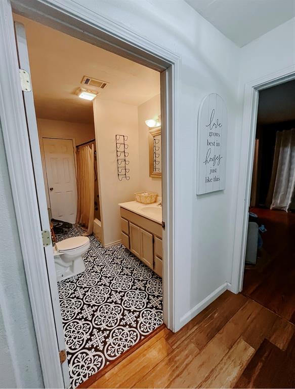 bathroom with hardwood / wood-style flooring, curtained shower, toilet, and vanity