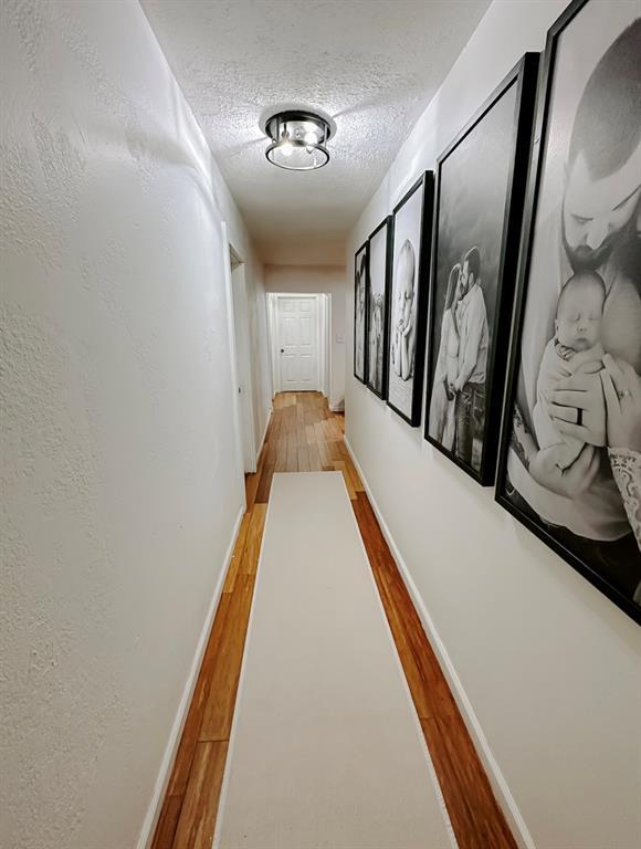 hallway with wood-type flooring and a textured ceiling