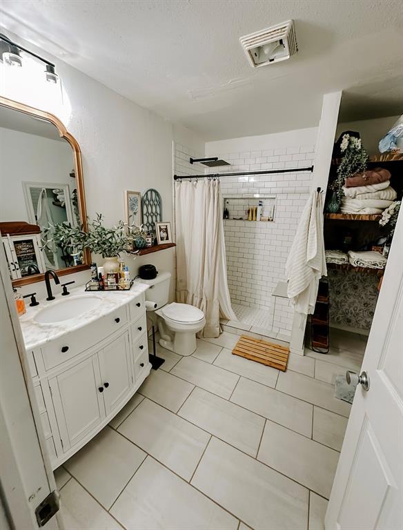 bathroom with toilet, a shower with curtain, tile patterned floors, and vanity