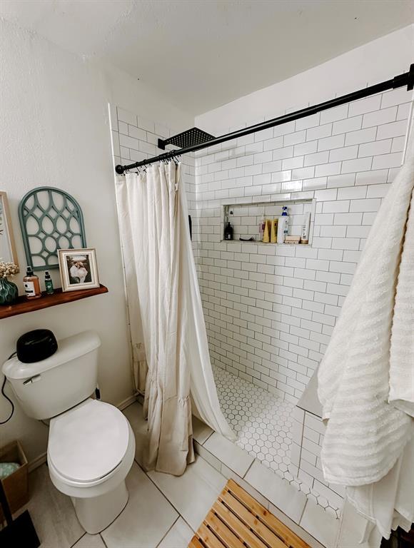 bathroom with toilet, tile patterned flooring, and curtained shower