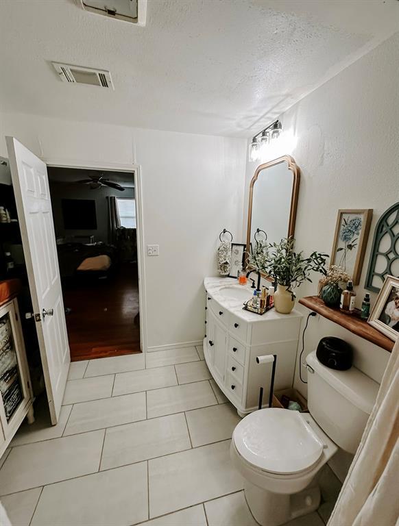 bathroom with a textured ceiling, tile patterned floors, vanity, toilet, and ceiling fan