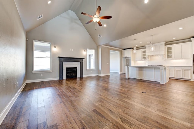 unfurnished living room featuring ceiling fan, sink, high vaulted ceiling, and dark hardwood / wood-style flooring