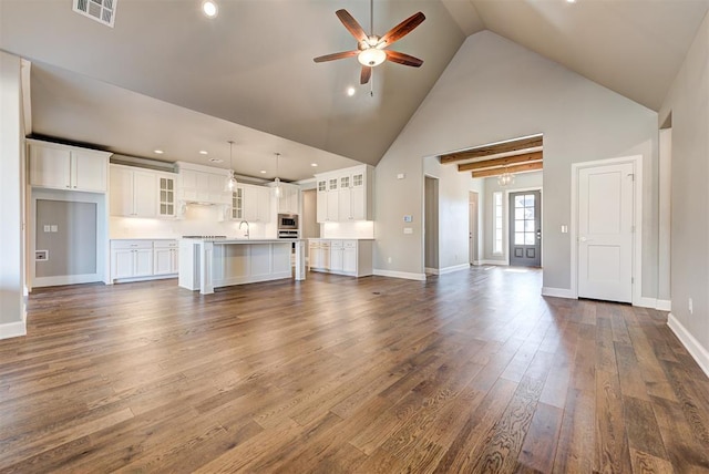 unfurnished living room with ceiling fan, a towering ceiling, dark hardwood / wood-style floors, and sink