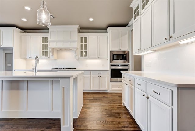 kitchen with sink, hanging light fixtures, a kitchen island with sink, stainless steel appliances, and white cabinets