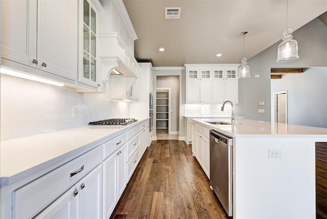 kitchen with pendant lighting, white cabinets, appliances with stainless steel finishes, an island with sink, and sink