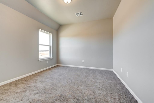 carpeted spare room featuring vaulted ceiling