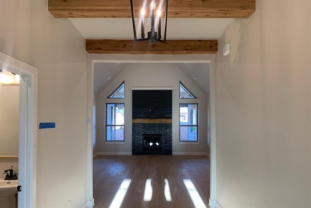 unfurnished living room featuring a brick fireplace, dark hardwood / wood-style floors, and beamed ceiling