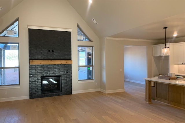 unfurnished living room featuring crown molding, light wood-type flooring, high vaulted ceiling, and a brick fireplace