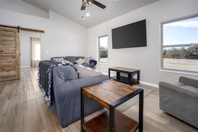 bedroom featuring baseboards, light wood-style floors, a barn door, and vaulted ceiling