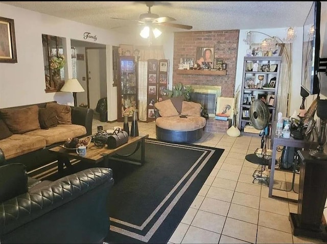 living room featuring ceiling fan, a fireplace, light tile patterned flooring, and a textured ceiling