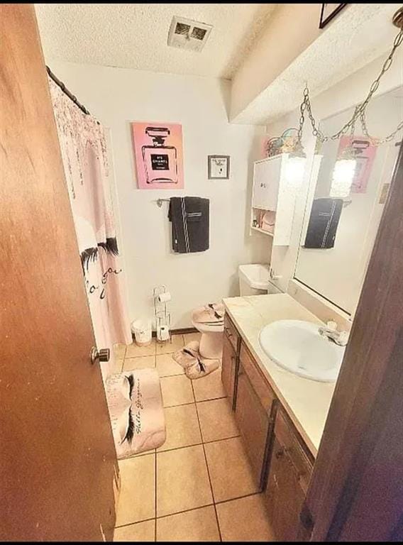 bathroom featuring a textured ceiling, toilet, tile patterned floors, and vanity