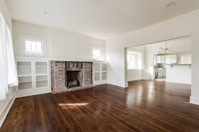 unfurnished living room with dark hardwood / wood-style flooring and a brick fireplace