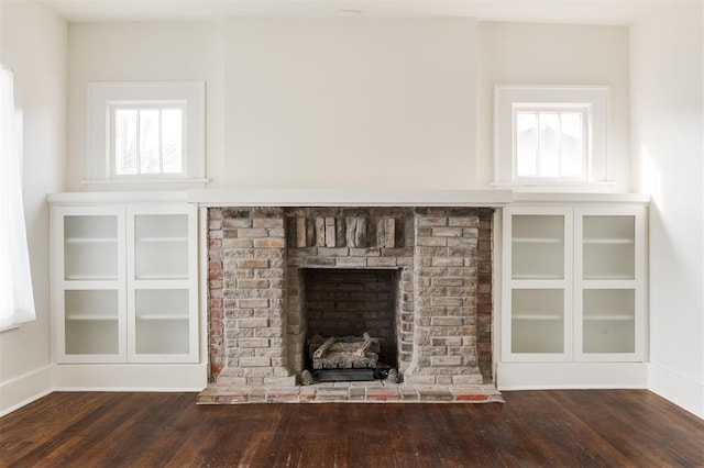 unfurnished living room with a brick fireplace and dark hardwood / wood-style flooring