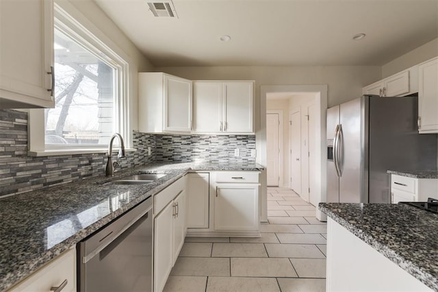 kitchen featuring sink, white cabinetry, light tile patterned floors, dark stone countertops, and stainless steel appliances