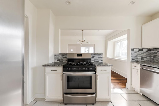 kitchen featuring backsplash, light stone countertops, white cabinets, and appliances with stainless steel finishes