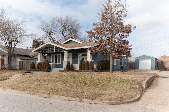 view of front of home featuring a garage, an outdoor structure, covered porch, and a front lawn