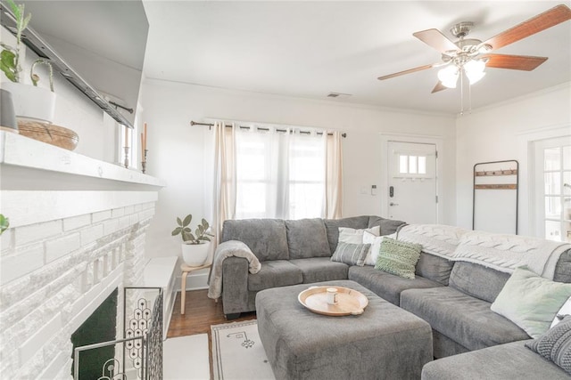 living room featuring a wealth of natural light, visible vents, crown molding, and wood finished floors