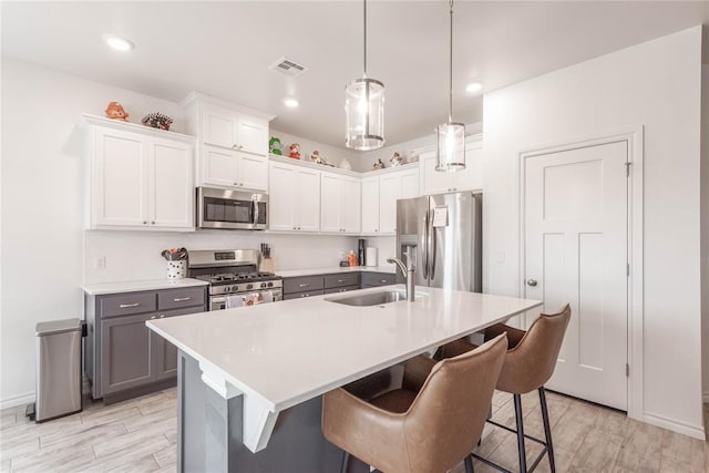 kitchen featuring white cabinets, appliances with stainless steel finishes, sink, hanging light fixtures, and gray cabinetry