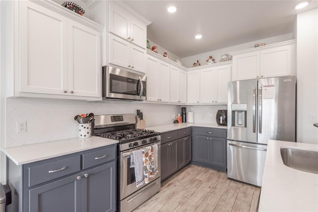 kitchen featuring stainless steel appliances, light hardwood / wood-style floors, white cabinetry, and gray cabinets