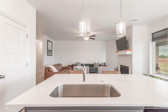 kitchen with sink, pendant lighting, and a kitchen island with sink