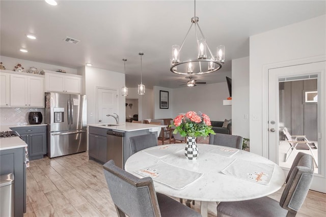 dining room featuring sink, ceiling fan with notable chandelier, and light hardwood / wood-style floors