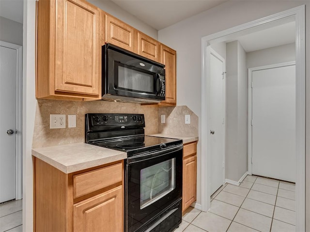 kitchen with light tile patterned flooring, backsplash, light brown cabinetry, and black appliances