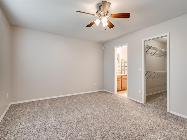 unfurnished bedroom featuring ceiling fan, carpet, connected bathroom, a walk in closet, and a closet