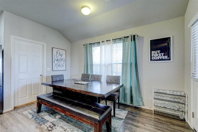 dining room with hardwood / wood-style floors and vaulted ceiling