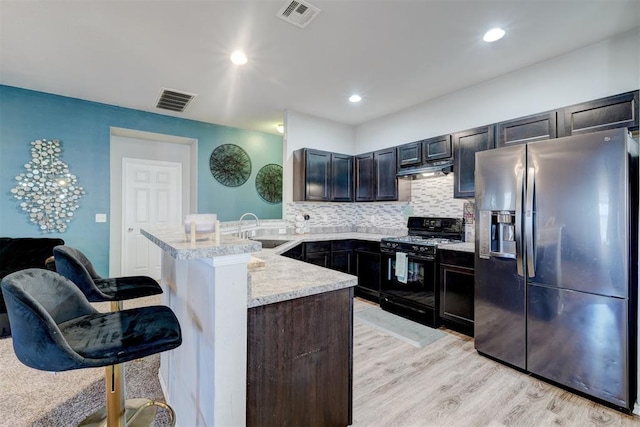 kitchen with gas stove, sink, a kitchen breakfast bar, kitchen peninsula, and stainless steel refrigerator with ice dispenser