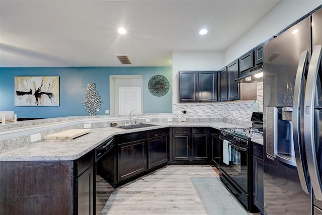 kitchen featuring black appliances, sink, backsplash, light hardwood / wood-style floors, and kitchen peninsula