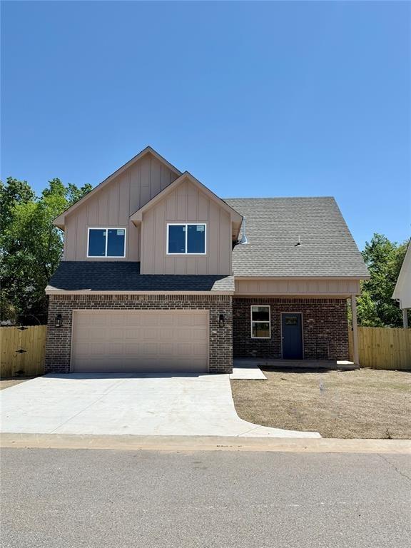 view of front of home with brick siding, driveway, a garage, and fence