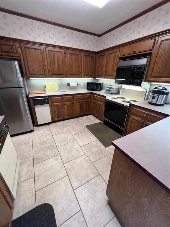 kitchen with black microwave, range with electric cooktop, freestanding refrigerator, and wallpapered walls