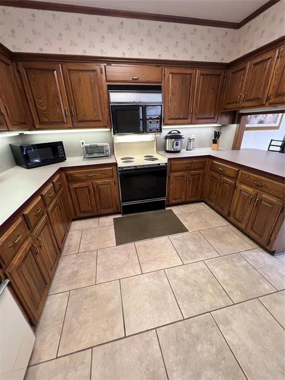 kitchen with wallpapered walls, range with electric cooktop, light countertops, and black microwave