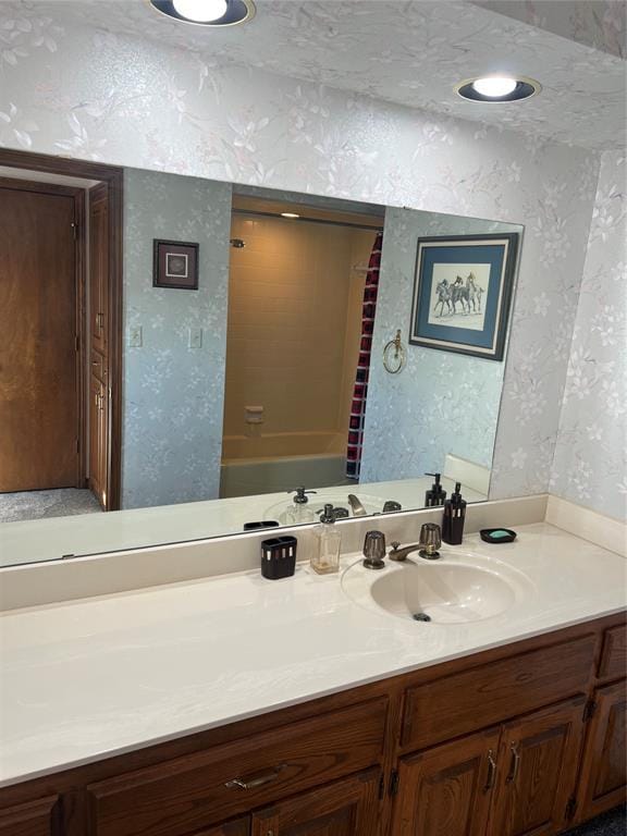 bathroom featuring wallpapered walls, vanity, and a textured wall